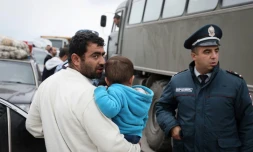 Un réfugié portant un enfant s'entretient avec un policier près de la ville frontalière de Kornidzor, en Arménie, le 25 septembre 2023
