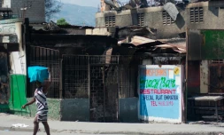 Une femme passe devant un un rstaurant brûlé par des bandes armées, le 12 mars 2024 à Port-au-Prince, en Haïti