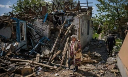 Un couple emporte ses bagages et quitte sa maison entièrement détruite à Vilkhivka, à l'est de Kharkiv (Ukraine), le 14 mai 2022


