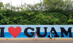 Des touristes passent devant une affiche "I love Guam", sur l'île de Guam dans l'océan pacifique, le 11 août 2017