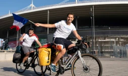 Mehdi Balamissa (à droite) et Gabriel Martin agitent des drapeaux français avant leur départ le 20 août 2022 du Stade de France vers Doha, en vélo, pour aller encourager les Bleus à la Coupe du monde 2022 au Qatar