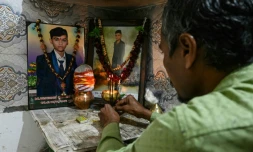 Suresh Patni, père d'Akash Patni, victime du crash du vol 171 d'Air India d'Air India, prie devant les portraits de son fils à son domicile d'Ahmedabad, le 8 novembre 2025 en Inde