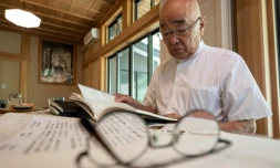 Le prêtre bouddhiste Eiichi Shinohara regarde le journal d'une femme qui s'est fait escroquer des millions de yens, lors d'une interview avec l'AFP dans son temple à Narita, à l'est de Tokyo, le 5 septembre 2023