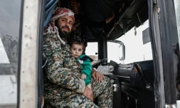 Un combattants rebelle syrien évacué de la ville de Doumeir, au nord-est de Damas, tient dans les bras son fils dans un bus arrivant à Azaz, dans le nord du pays le 20 avril 2018