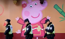 Des policiers passent devant l'effigie de Peppa Pig sur un mur, le 25 janvier 2019 à Shanghai