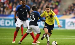 Le milieu français Paul Pogba (g) regarde son homologue N'Golo Kanté (c) à la lutte avec le milieu colombien James Rodriguez lors d'un amical au Stade de France, à Saint-Denis, le 23 mars 2018