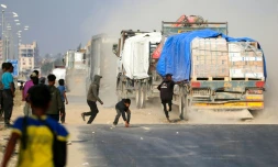 Un Palestinien tente de monter à bord d'un camion circulant sur la route Salah al-Din, dans le centre de la bande de Gaza, près de Deir al-Balah, alors que des personnes tentent d'obtenir de l'aide humanitaire, le 9 novembre 2025