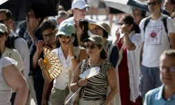 Des touristes avec des éventails devant la cathédrale Notre-Dame, le 16 août 2025 à Paris