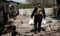 Un policier ukrainien apporte de la nourriture à des habitants de Novomykolaïvka, dans l'est de l'Ukraine, le 11 mai 2022
