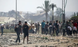 Des déplacés palestiniens portent des produits alimentaires obtenus à un point de distribution du centre de la bande de Gaza, le 26 juillet 2025