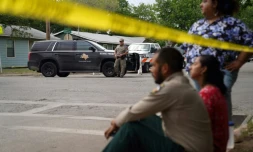 Des habitants, sonnés, assis sur le trottoir non loin de l'école primaire endeuillée, à Uvalde, au Texas, le 24 mai 2022