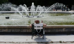 Un homme prend le soleil près d'une fontaine du jardin du Palais Royal, lors d'un pic de chaleur, le 31 juillet 2020 à Paris