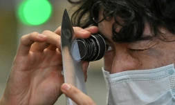 Un employé du fabricant japonais de couteaux Sumikama inspecte une lame à l'aide d'une loupe dans son usine de Seki, au Japon, le 22 juillet 2025