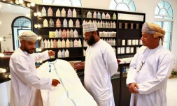 Un vendeur de dishdashas, robe traditionnelle portée par les hommes à Oman, montre un modèle à des clients, le 10 janvier 2022 à Mascate