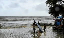 Des hommes transportent leur atelier de fortune au bord de la mer à titre préventif lors des pluies à Kuakata le 26 mai 2024, avant l'arrivée dimanche soir du cyclone Remal au Bangladesh. 