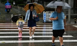 Des personnes s'abritent de la pluie avec des parapluies à Pékin, le 30 juillet 2023. La Chine a placé une partie du nord du pays en alerte rouge, y compris la région de Pékin, en raison de pluies torrentielles attendues suite à l'avancée du typhon Doksuri.