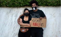 Un couple pose avec un Ă©criteau qui demande "ArrĂȘter de nous tuer", Ă Los Angeles le 27 mai 2020, aprĂšs la mport de George Floyd, un AfroamĂ©ricain asphixiĂ© par la police lors d'une interpellation
