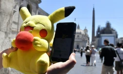 Un joueur tient une mascotte de Pokémon et joue au Pokémon Go sur son portable, le 19 juillet 2016 à Rome.