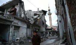 Un enfant marche dans une rue bordée de maisons détruites, le 9 janvier 2017 à Douma, près de Damas, en Syrie