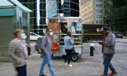 Des passants, photographiés le 30 septembre, devant le stand de café et de petits déjeuner d'Abdul Rahman, à New York
