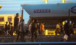 Des migrants marchent sur la voie ferrée en direction du terminal d'Eurotunnel le 11 août 2015 à Fréhun