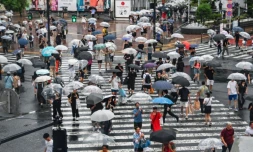 Des piétons s'abritent de la pluie, à l'approche du typhon "Ampil", le 16 août 2024 à Tokyo