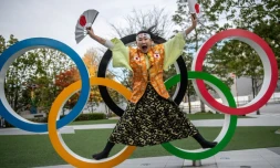 La fan des Jeux olympiques Kyoko Ishikawa pose devant les anneaux installés devant le nouveau stade olympique national à Tokyo, le 19 décembre 2020.