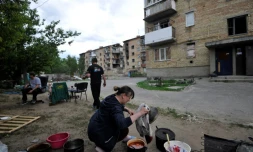 Une femme ukrainienne prépare à manger dans la rue, devant son immeuble bombardé et privé d'électrivité et de gaz, dans la petite ville de Moshchun, près de Kiev, le 27 mai 2022
