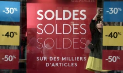 Une vendeuse s'occupe de la vitrine d'un magasin au lancement de la saison des soldes d'été le 22 juin 2016 à Strasbourg. Les pancartes affichent des réductions de 30, 40 et 50%