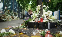 Une femme se recueille devant les fleurs déposées à la mémoire des victimes d'une fusillade à l'école Vladislav Ribnikar, le 4 mai 2023 à Belgrade, en Serbie