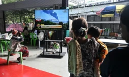 Des personnes déplacées par les combats à la frontière aavec le Cambodge regardent les informations à la télévision dans un centre pour évacués dans la province thaïlandaise de Surin, le 11 décembre 2025