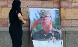 Une femme regarde un portrait de l'ancien chef militaire des Serbes de Bosnie, Ratko MladiÄ, devant la cathĂ©drale orthodoxe de Banja Luka, en Bosnie, le 28 aoĂ»t 2026, au lendemain de sa mort Ă l'Ăąge de 84 ans dans un hĂŽpital pĂ©nitentiaire de La Haye