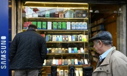Un homme regarde la vitrine d'un magasin de téléphones à Damas, le 12 janvier 2025 en Syrie