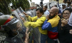 Carlos Paparoni (C) and Marco Bozo (D), députés d'opposition, face à la police, à Caracas, le 30 mars