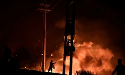 Un homme tente de lutter contre le feu avec un extincteur, le 3 août 2021 à Dekelia, au nord d'Athènes
