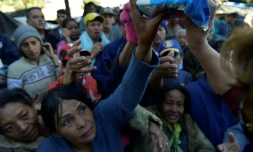Des Vénézuéliens, installés dans un campement de fortune près d'une gare de bus, reçoivent un peu de nourriture, le 9 août 2018 à Quito, en Equateur