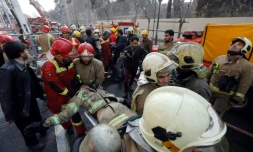 Un pompier blessé évacué après l'effondrement d'un immeuble de 15 étages le 19 janvier 2017 à Téhéran
