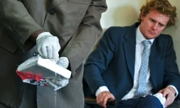 L'aristocrate britannique, Jack Alexander Wolf Marrian (D), accusé du trafic de 100 kilos de cocaïne depuis le Brésil vers le port de Mombasa, face à une plaquette de cocaïne présentée comme preuve, le 11 novembre 2016 au siège du Département d'enquête criminelle de Nairobi