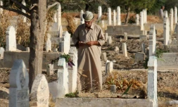 Un Syrien lit le coran sur les tombes de proches et de membres de sa famille au premier jour de l'Aïd al-Adha, la grande fête musulmane du sacrifice, le 1er septembre 2017 à Binnish (Syrie)

