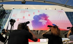 Des employés installent l'affiche officielle du 78e Festival de Cannes sur la façade du Palais des Festivals à Cannes, dans le sud-est de la France, le 11 mai 2025