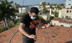 William Roblejo joue du violon sur le toit de sa maison, le 15 avril 2020 Ă La Havane, Ă Cuba