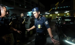 Un policier bloque les journalistes pendant qu'un membre de l'ambassade de Corée du Nord quitte en voiture le département de médecine légale où se trouve le corps de Kim Jong-Nam, demi-frère du leader nord-coréen Kim Jong-Un, le 15 février 2017 à Kuala Lumpur, en Malaisie