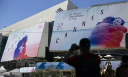 Un piéton prend une photo des affiches de la 78e édition du Festival de Cannes devant le Palais des Festivals à Cannes, dans le sud de la France, le 12 mai 2025