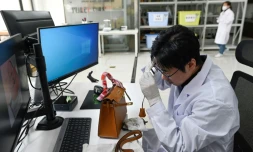 Zhang Chen vérifie à la loupe l'authenticité d'un sac dans les locaux de son établissement, l'Ecole commerciale des grands produits de luxe, le 24 mars 2021 à Pékin, en Chine