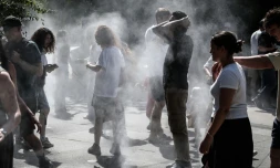 Des personnes se rafraîchissent au milieu de brumisateurs à Paris, le 1er juillet 2025, en période de canicule