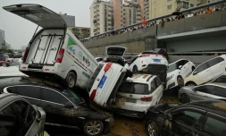 Des habitants regardent des véhicules amoncelés après les pluies diluviennes sur Zhengzhou, dans le centre de la Chine, le 22 juillet 2021