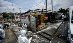 Des employés municipaux en combinaison de protection contre le coronavirus nettoient les rues de Petare, un quartier de Caracas, le 2 avril 2020 au Venezuela