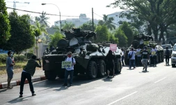 Des manifestants se rassemblent prÚs des blindés déployés dans le centre de Rangoun, le 15 février 2021