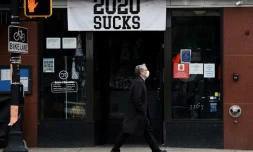 Un homme portant un masque passe devant un restaurant orné d'une banniÚre "2020 craint", le 18 décembre 2020 à Arlington, en Virginie (Etats-Unis)