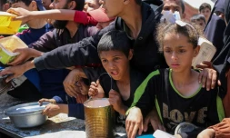 Des enfants palestiniens font la queue pour obtenir un repas chaud lors d'une distribution assurée par une cuisine soldiaire au camp de réfugiés de Nousseriat, dans le centre de la bande de Gaza, le 5 mai 2025